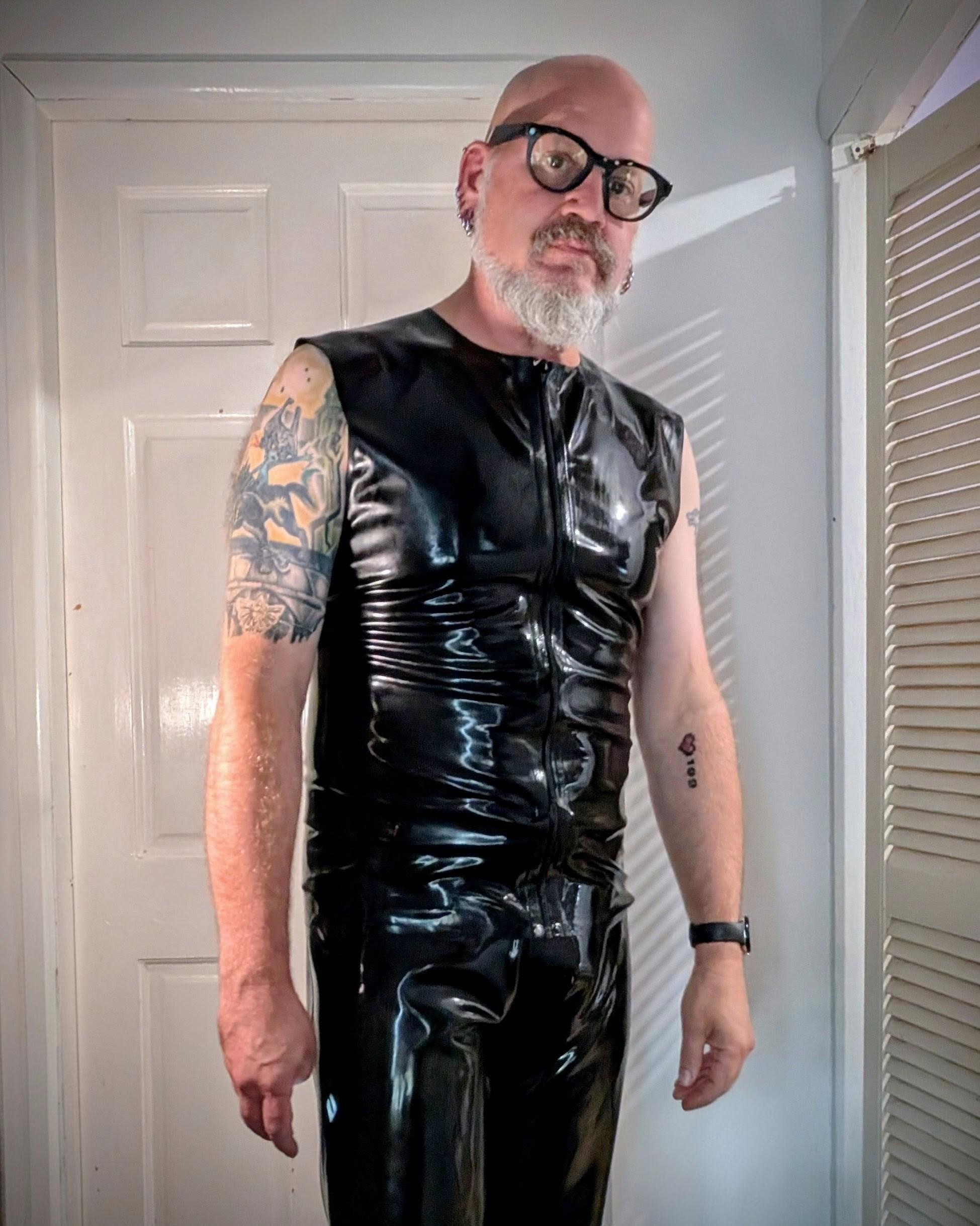Tipping the scales at around 95kg my belly is much smaller now, and the latex jeans (a smaller size than in the previous photo) are now looking somewhat loose on me. I'm wearing full latex. I'm a 53 year old male with a bald head, multiple piercings and tattoos.